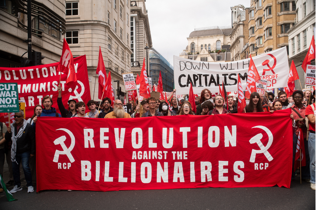 Marchers with red flags and a large banner saying 